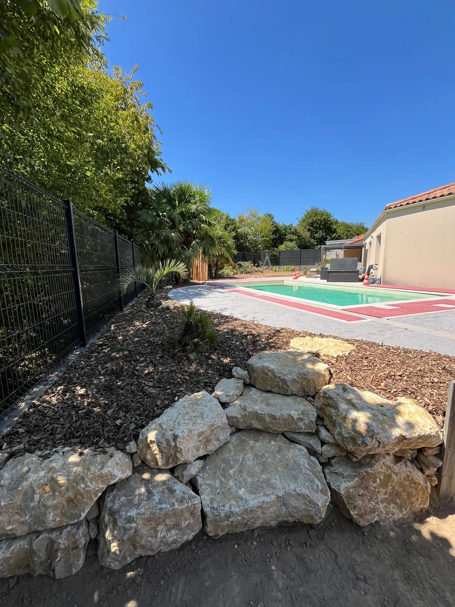 Muret en rochers naturels près d’une piscine paysagée
